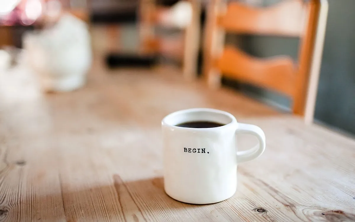 A white mug with the word Begin on a wooden table