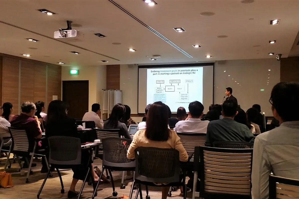 Dr Eugene Tan presenting on biologic treatment goals for psoriasis to a room of clinicians
